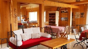 Un intérieur en bois avec un canapé rouge, une table à manger et un coin cuisine.