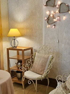 Ein Zimmer mit einem stahlrohrgestellten Sessel, einem Holznachttisch mit Lampe und einer Wand, die mit herzförmigen Lichtern dekoriert ist.