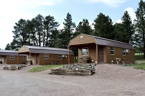 Ein rustikales Blockhaus mit Metalldach, einer Veranda und einem Schild mit der Nummer 24.