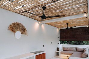 A modern room with a ceiling fan, a wall-mounted decorative piece, a sofa, and a small table. - Pleasant 2-bedroom house with AC in charming Kuta (Kuta, Central Lombok / Lombok Tengah)