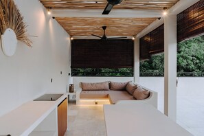 A modern room with a built-in sofa, ceiling fan, and a view of greenery outside. - Pleasant 2-bedroom house with AC in charming Kuta (Kuta, Central Lombok / Lombok Tengah)