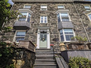 Un bâtiment en pierre avec une porte verte, de nombreuses fenêtres et un escalier menant à l’entrée.