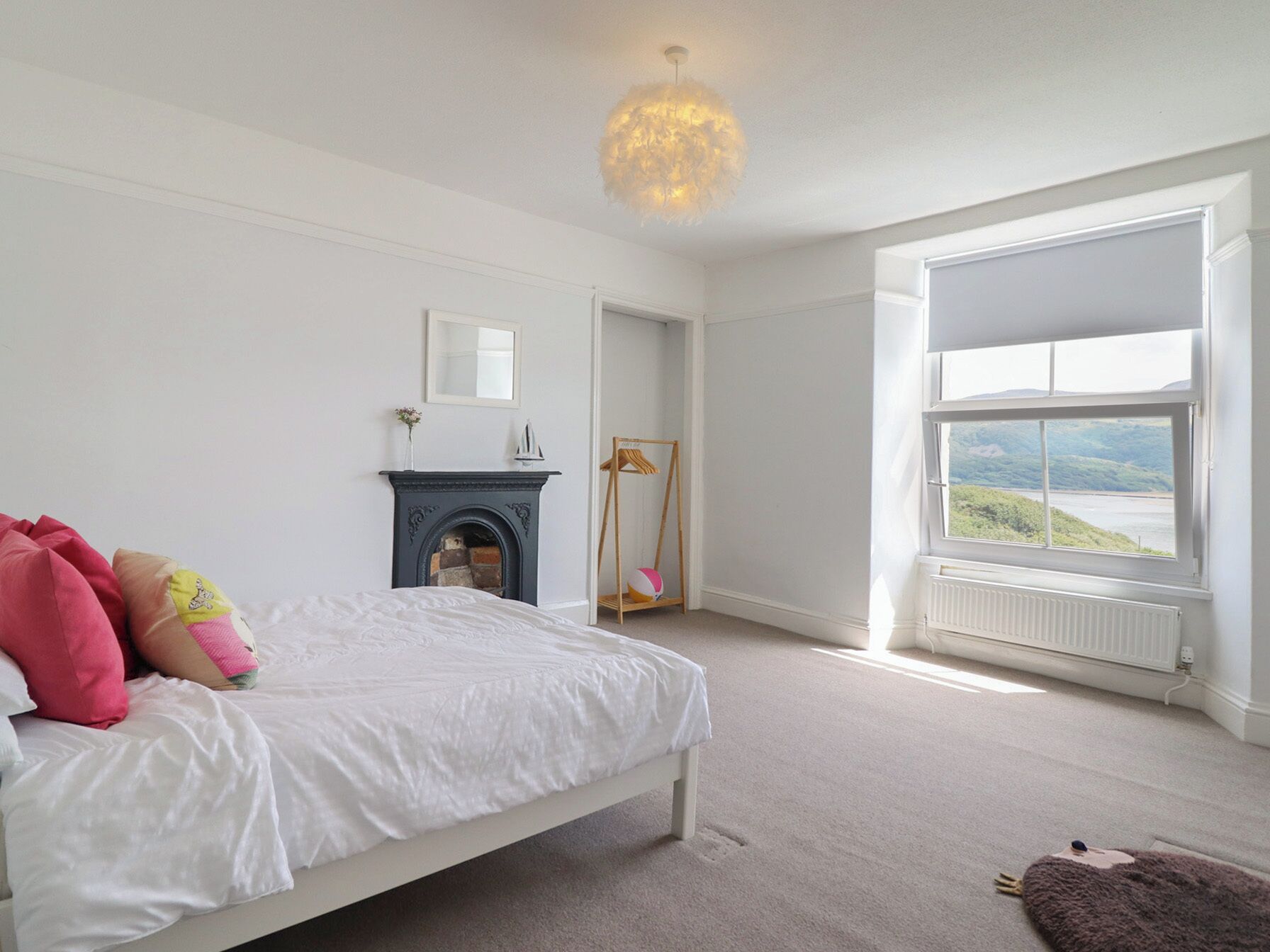 Un dormitorio con cama, chimenea, ventana con vistas y una lámpara colgante.