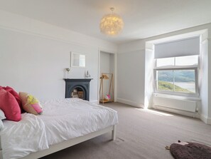 Un dormitorio con cama, chimenea, ventana con vistas y una lámpara colgante.