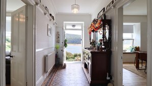 A hallway with patterned flooring, a view to the outside, and a window with a view of the outdoors. - 5 Porkington Terrace (Barmouth)