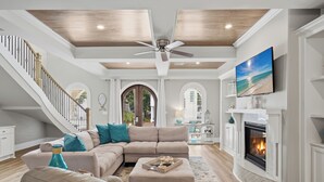 A spacious living room with a fireplace, a large TV, and a staircase. - Bikes, Gated Community, New Rental, Golf Cart, Hot Tub, Close to Beach (Santa Rosa Beach)