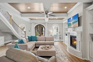 A spacious living room with a fireplace, a large TV, and a staircase. - Bikes, Gated Community, New Rental, Golf Cart, Hot Tub, Close to Beach (Santa Rosa Beach)