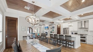 A modern kitchen with white cabinetry, a central island, and a dining area with a wooden table and chairs. - Bikes, Gated Community, New Rental, Golf Cart, Hot Tub, Close to Beach (Santa Rosa Beach)