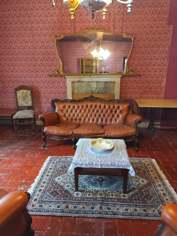 Une pièce avec un canapé en cuir marron, une table en bois sur laquelle se trouve un saladier, des tapis à motifs et un miroir au-dessus d’une cheminée.