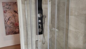A modern bathroom with a glass-enclosed shower, a white sink, and a decorative wall piece.