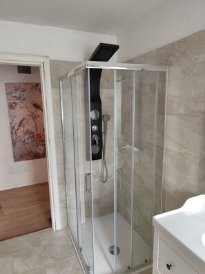 Une salle de bain moderne avec une douche à parois de verre, un lavabo blanc et un élément décoratif mural.