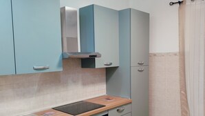 A compact kitchen with light blue cabinets, a wooden countertop, a built-in oven, and a ceiling light fixture.
