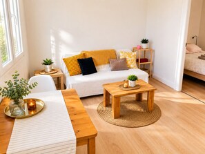 Ein gemütliches Wohnzimmer mit einer Couch, einem Couchtisch, einem Beistelltisch und einer kleinen Pflanze.