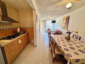 A kitchen with a stove, cabinets, and a dining area with a table and chairs. - 3-bedroom house in safe condo with pool and sun lounger (Acapulco de Juárez)
