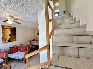 A staircase with wooden railings, a dining area with chairs and a table, and a ceiling fan. - 3-bedroom house in safe condo with pool and sun lounger (Acapulco de Juárez)