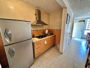 A kitchen with a stainless steel refrigerator, a gas stove, wooden cabinets, and a tiled backsplash. - 3-bedroom house in safe condo with pool and sun lounger (Acapulco de Juárez)