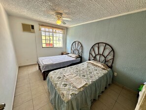 A bedroom with two beds, a ceiling fan, a window, and a door. - 3-bedroom house in safe condo with pool and sun lounger (Acapulco de Juárez)