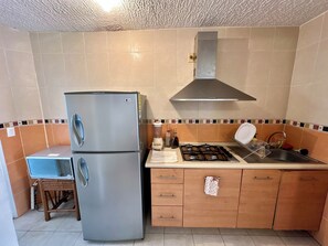 A kitchen with a double-door refrigerator, a gas stove, wooden cabinets, and a tiled backsplash. - 3-bedroom house in safe condo with pool and sun lounger (Acapulco de Juárez)