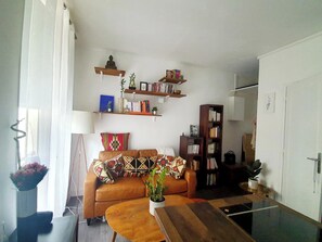 A living room with a sofa, coffee table, and bookshelves. - Apartment in Buttes-Chaumont with courtyard (Paris)