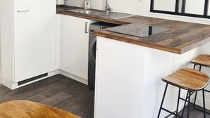 Een moderne keuken met witte kasten, een ingebouwde oven, een vaatwasser en een houten kookeiland met barstoelen.
