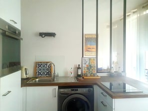A compact kitchen with a washing machine, a sink, and a small countertop. - Apartment in Buttes-Chaumont with courtyard (Paris)