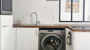 Een kleine keuken met een wasmachine, een magnetron en een spoelbak.