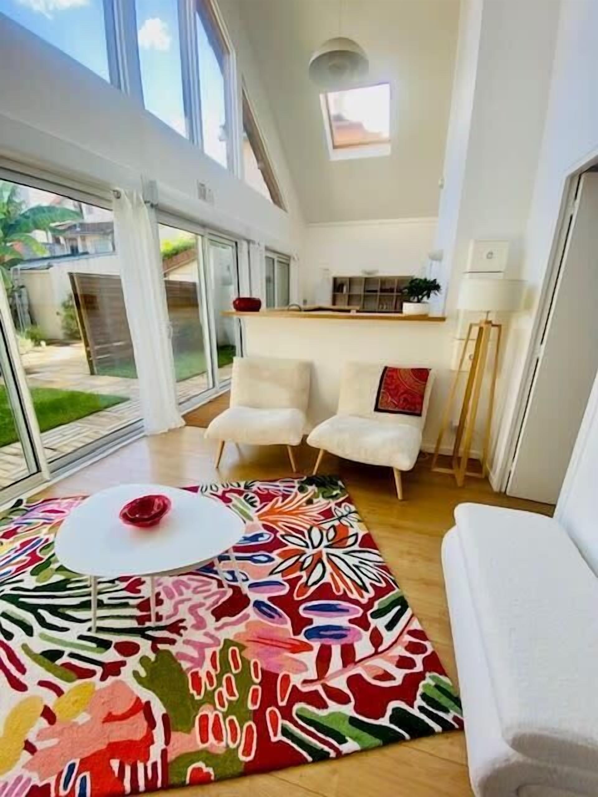 Une pièce moderne avec une grande fenêtre, un tapis à motifs et un canapé blanc.