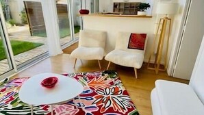 Ett modernt rum med ett stort fönster, en mönstrad matta och en vit soffa.