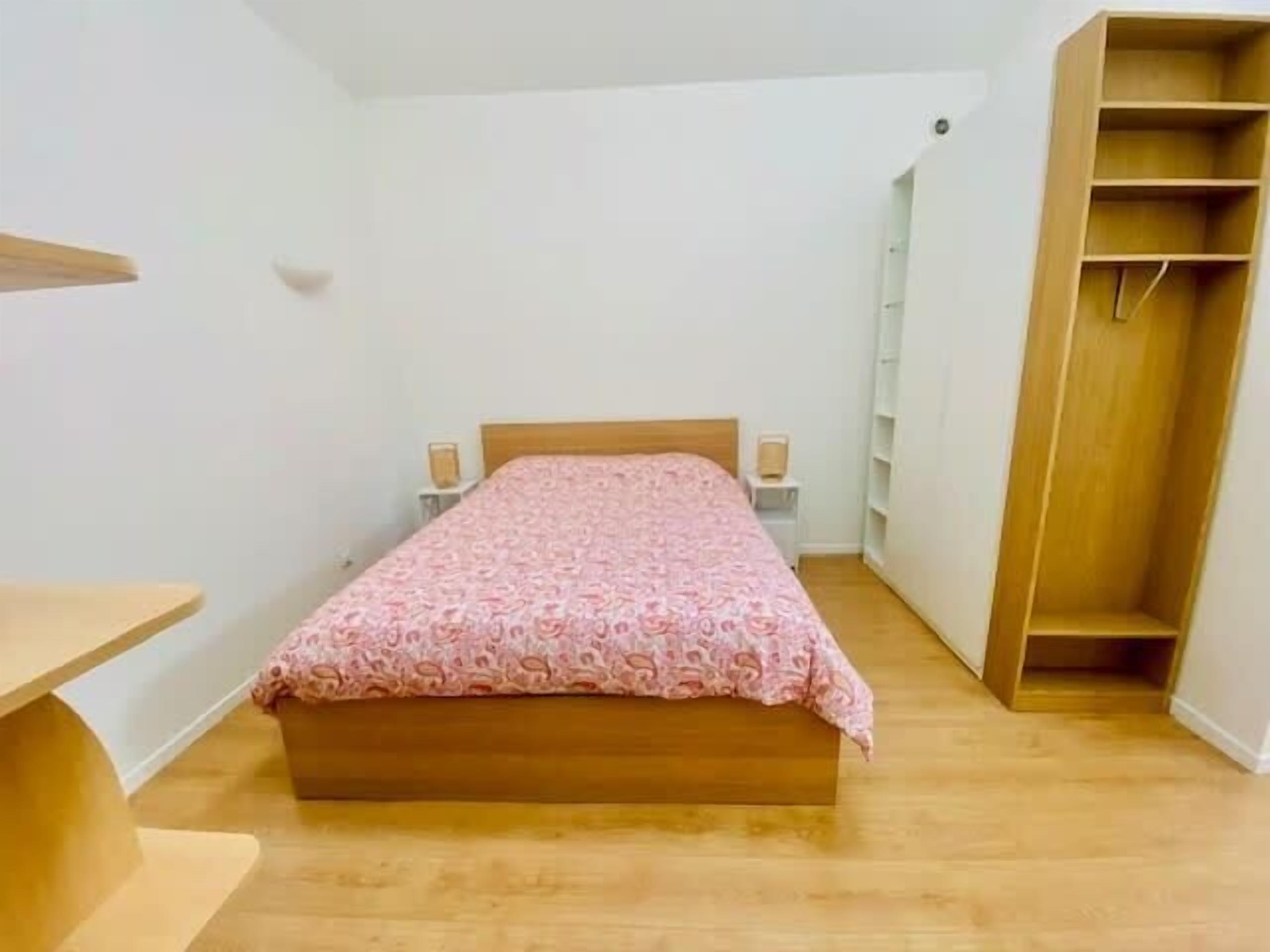 Une chambre à coucher avec un lit en bois, une table de chevet, une armoire et une petite étagère.