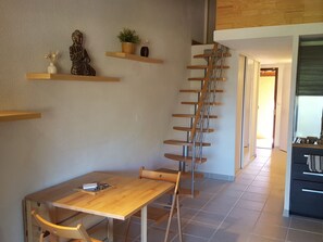 Eine Treppe mit Holzboden und Metallgeländern, ein Holztisch mit einem Stuhl sowie eine Küchenzeile mit Spüle und Schränken.