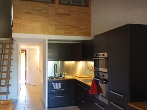 Eine moderne Küche mit dunklen Schränken, einer Holzarbeitsplatte, einem eingebauten Backofen und einem Edelstahlarmaturen.