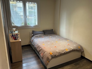 Ein Schlafzimmer mit einem Bett, einem Nachttisch, einem Fenster und Blick ins Freie.