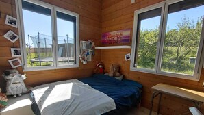 Une pi èce aux murs lambrissés, avec un lit, un bureau et deux fenêtres.