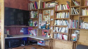Un salon avec un canapé, une table basse, un téléviseur et une bibliothèque remplie de livres.
