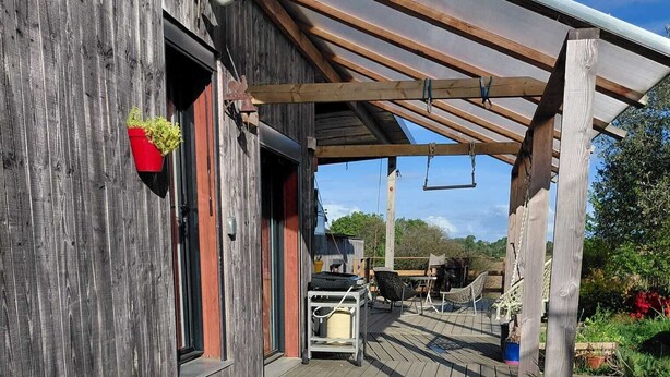 Un bain à remous dans un espace extérieur en bois, surmonté d’une pergola.