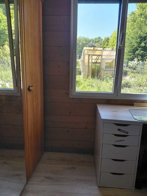 A room with wooden walls, a window with a view of greenery, and a desk with drawers. - Wooden house with a large deck and a 5-person hot tub, not overlooked (Nivillac)