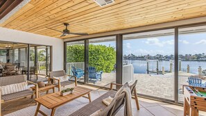 Een ruim balkon met uitzicht op een jachthaven, voorzien van buitenmeubels en een plafondventilator.