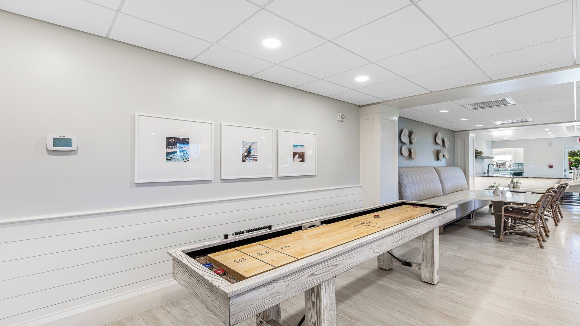 A modern interior with a foosball table, framed pictures on the wall, and a seating area with a sofa and chairs.