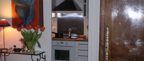 Un espacio habitable compacto con kitchenette, una puerta de madera y un cuadro en la pared.
