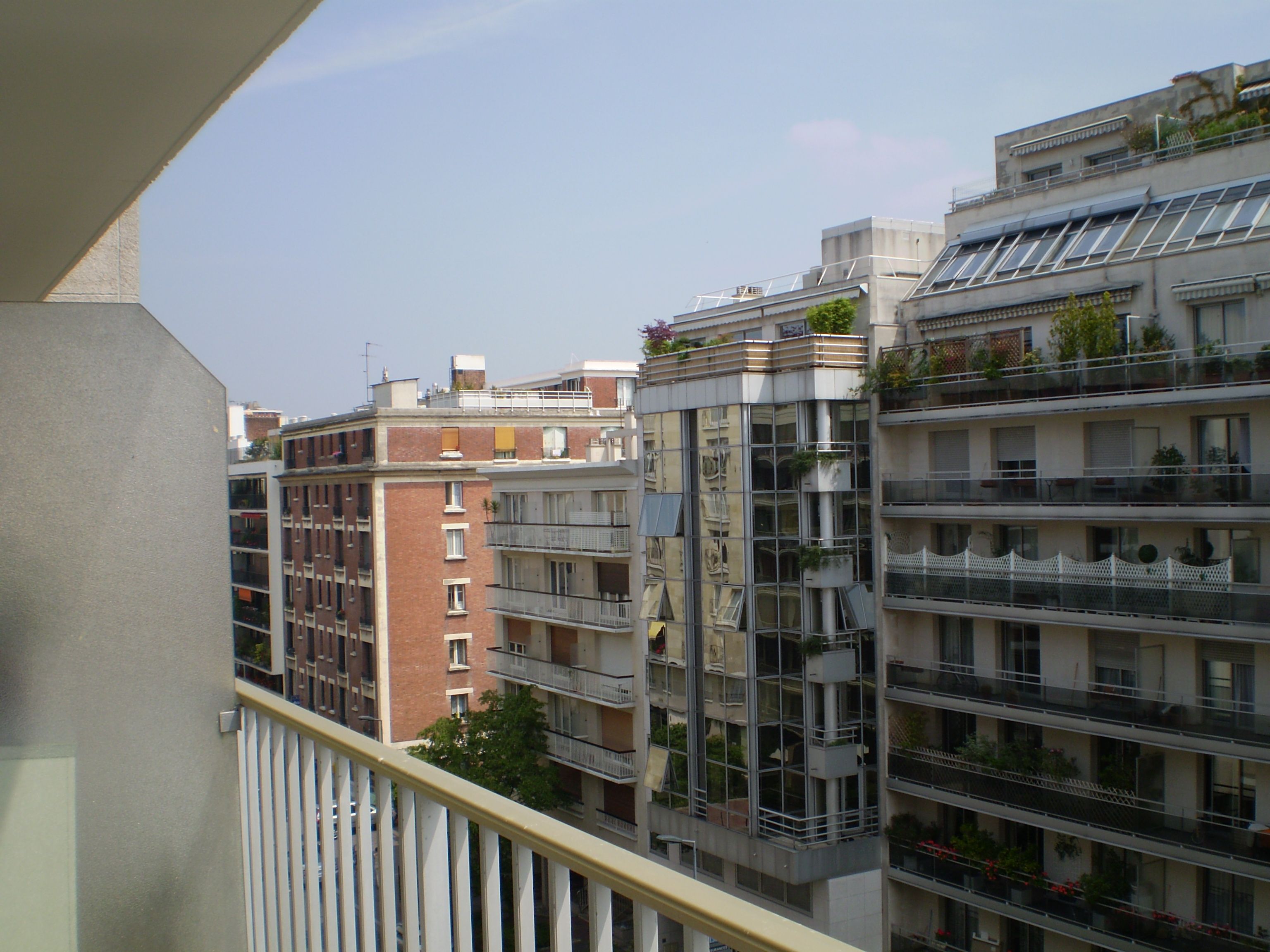A multi-story residential building with balconies, large windows, and a clear sky.
