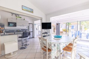 Une cuisine moderne avec un coin repas, un téléviseur à écran plat et une vue sur l’extérieur.