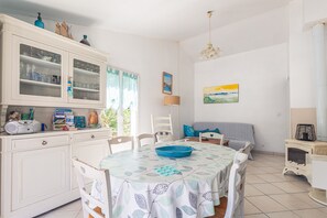 Ein Essbereich mit einem Tisch für zwei Personen, einem Schrank mit Gläsern und einem Bild an der Wand.