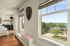 Ein modernes Wohnzimmer mit großem Fenster, einer Bank und Blick auf eine Brücke und Grünflächen.
