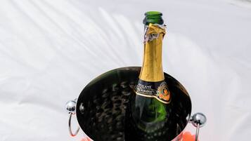 A bottle of champagne in a bucket with ice cubes on a white surface.