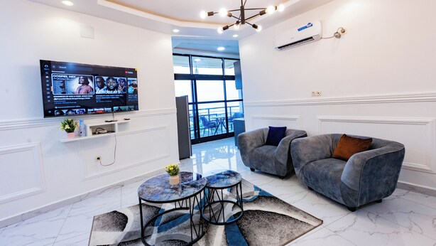 A modern living room with a flat-screen TV, grey sofa, and a coffee table. - MOONLIGHT HEAVEN (Limbe)