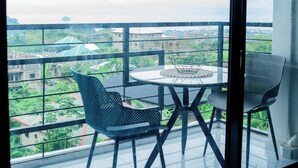 A balcony with a glass partition, two chairs, and a table. - MOONLIGHT HEAVEN (Limbe)