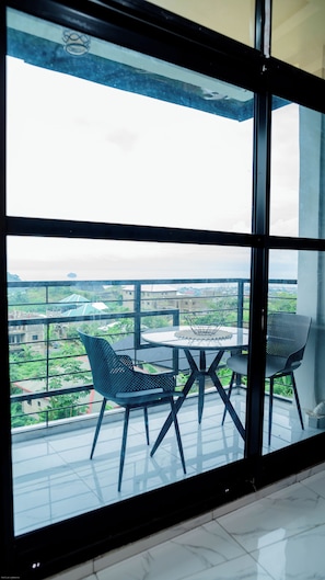 A balcony with a glass partition, two chairs, and a table. - MOONLIGHT HEAVEN (Limbe)