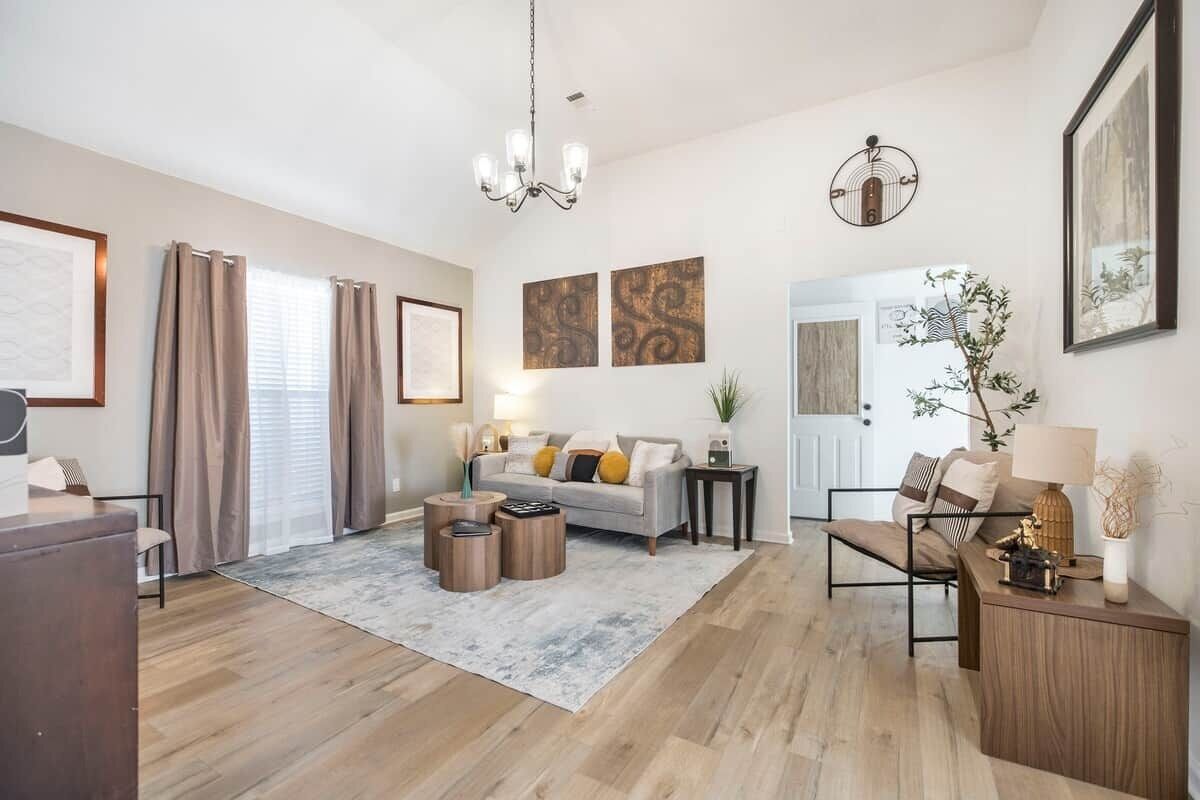 A modern living room with a sofa, coffee table, and side table, a chandelier, and artwork on the walls.
