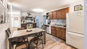 A modern kitchen with wooden cabinets, a white refrigerator, and a dining area with a wooden table and chairs.