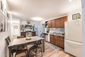 A modern kitchen with wooden cabinets, a white refrigerator, and a dining area with a wooden table and chairs.